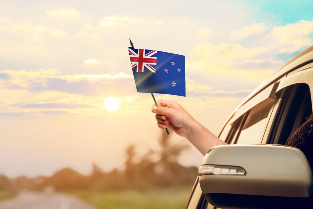 a person holding a NZ flag out of the window