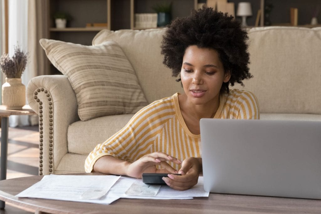 Woman using a computer and calculator to explore bad credit loan options with East Bay Finance.