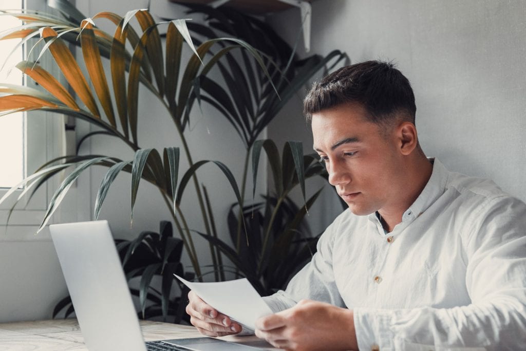 Man reviewing loan options on paper with a laptop — secured loans for bad credit from East Bay Finance